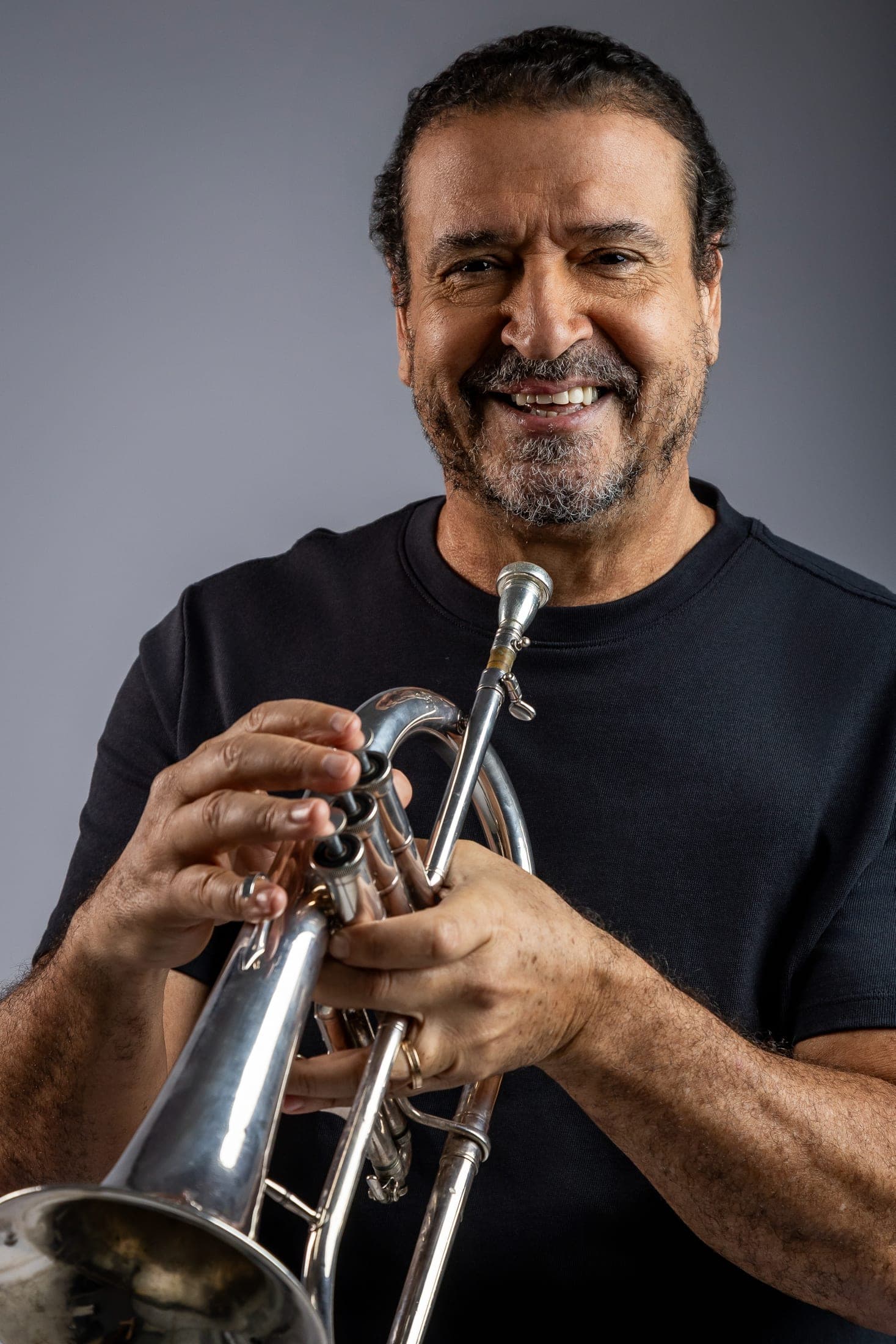 Silvério Pontes sorrindo de camiseta preta, segurando o flugelhorn