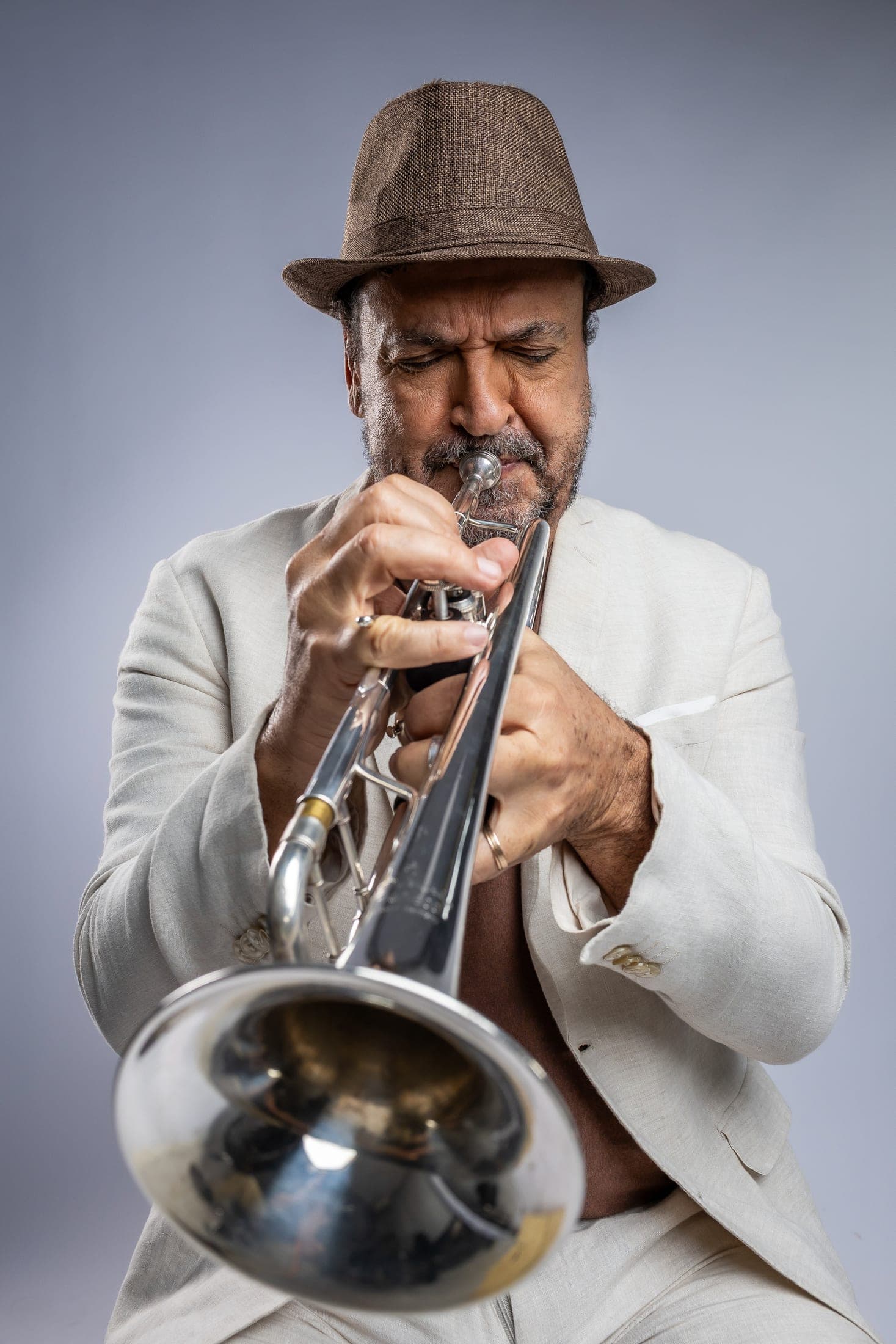 Silvério Pontes de terno claro e chapéu, tocando trompete